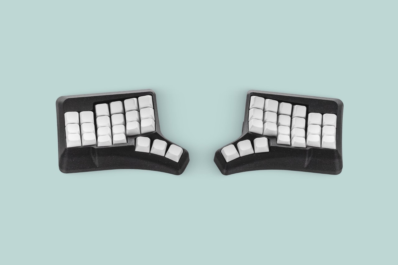 Phenom Mini split ergonomic keyboard with white keycaps in a black sculpted case