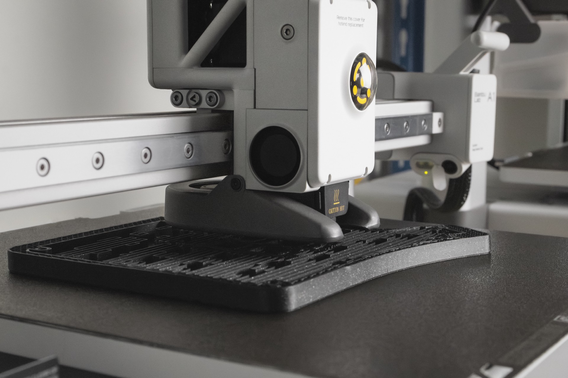 Close-up of a 3D printer producing the sculpted black Phenom case layer by layer